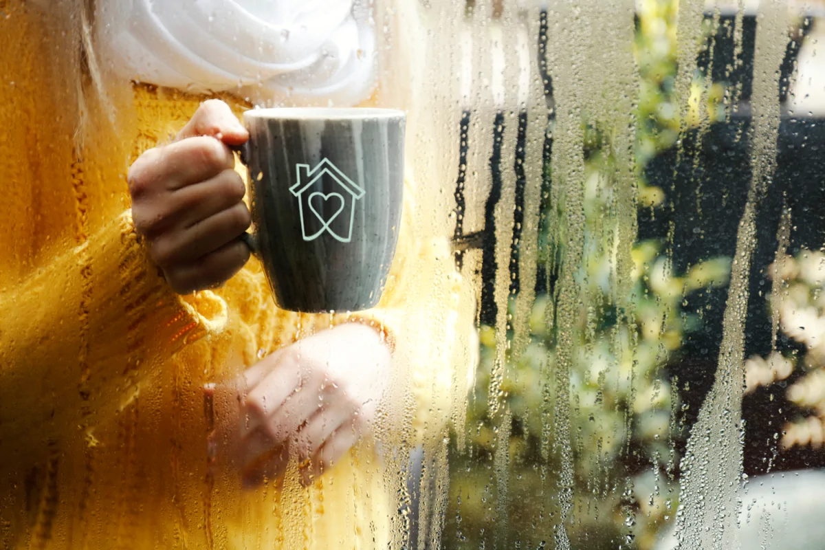 Woman holding a mug behind glass with condensation