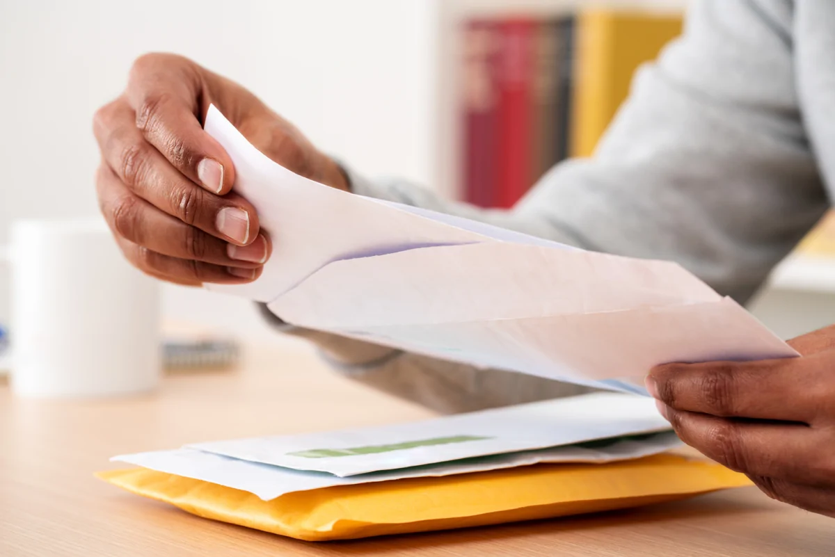 Person opening a letter whilst sat at table