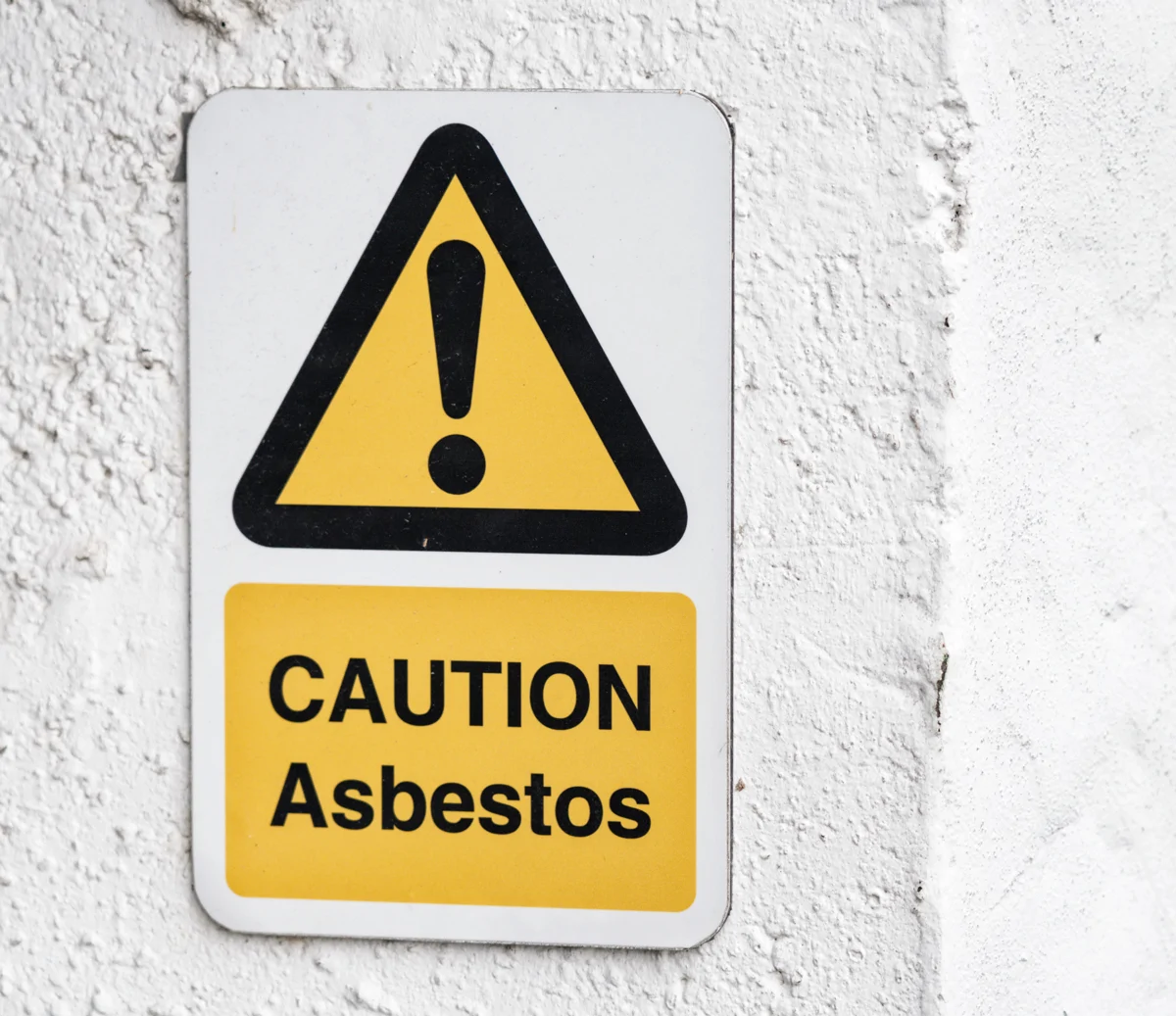 A yellow warning sign saying caution asbestos
