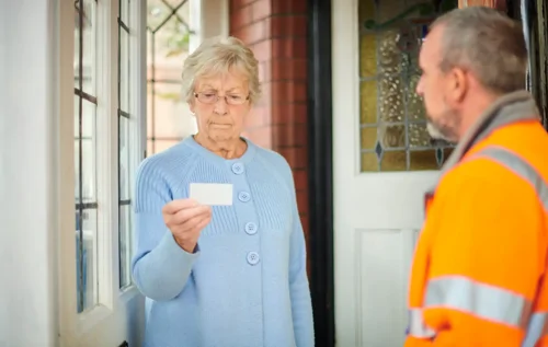 Women checks business card of male salesman at her front door