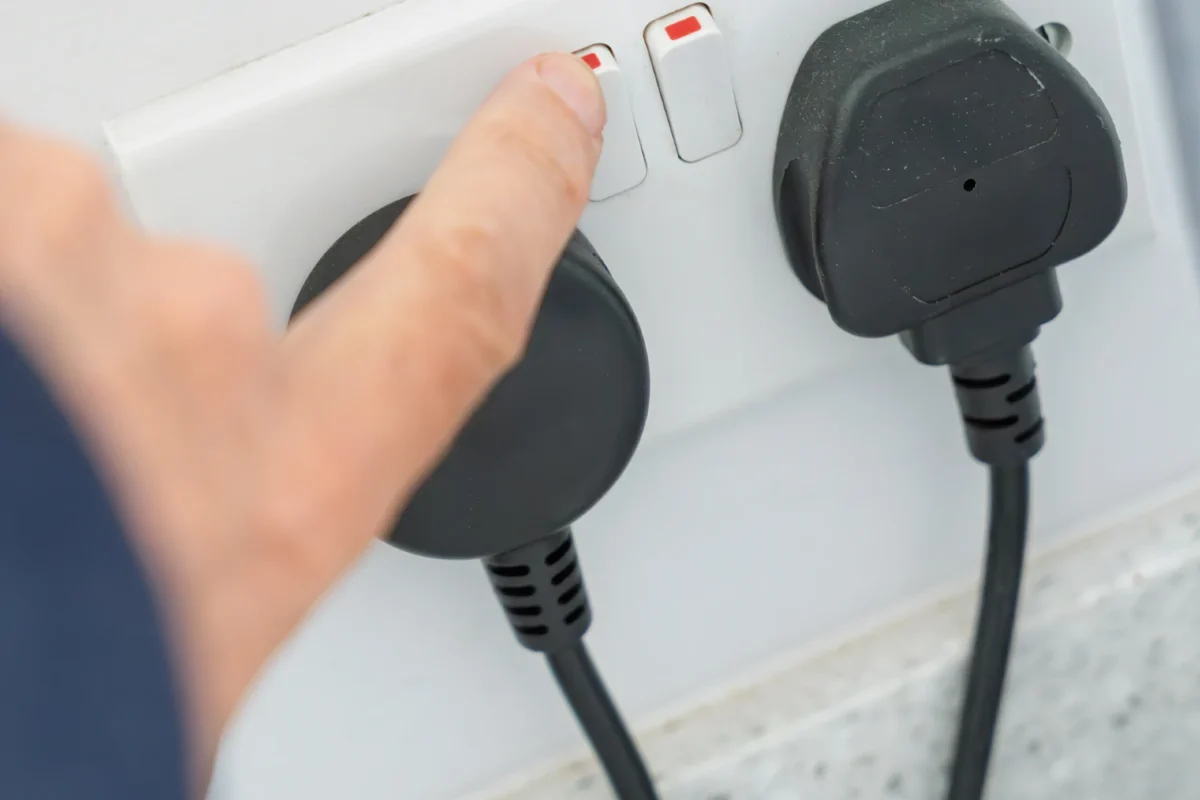 Person switching off electrical switch on double plug socket