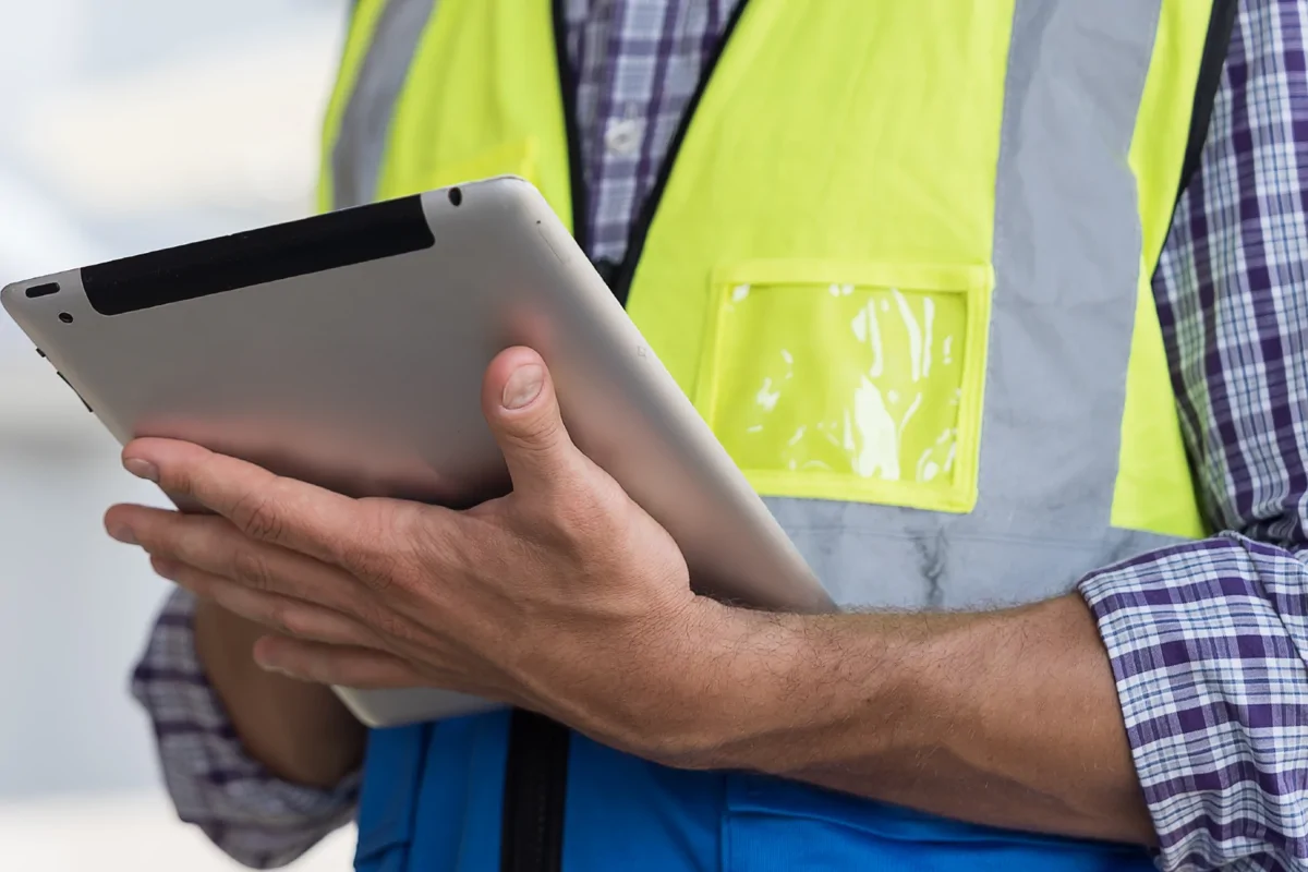 Surveyor wearing a hi-vis jacket and holding an ipad