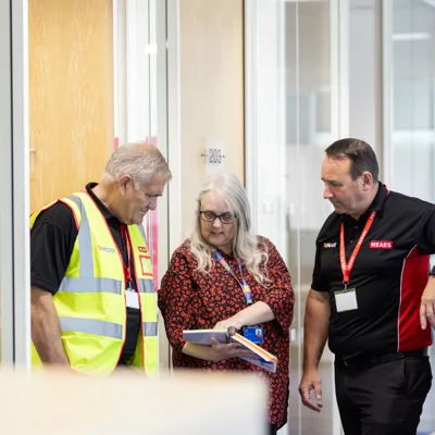 Moat and Mears colleagues stand together looking at notebook