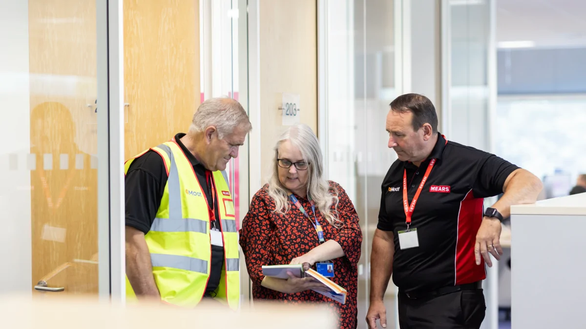 Moat and Mears colleagues stand together looking at notebook
