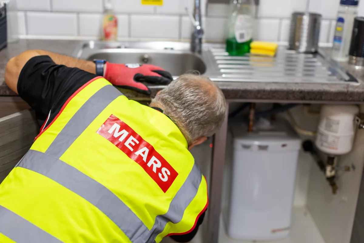 Mears operative fixing something under a kitchen sink