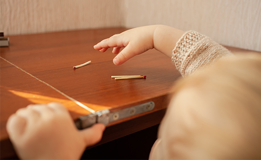 Small child reaching up for matches on table
